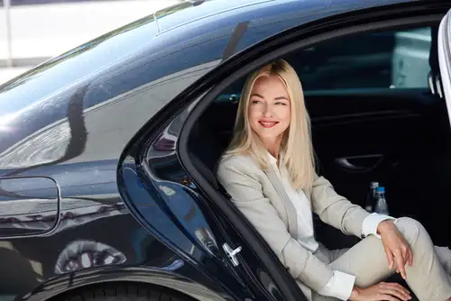 A stylish businesswoman waits inside a luxurious car for her personal private driver. Experience the convenience of our black car service for your next business trip. Book a ride now.