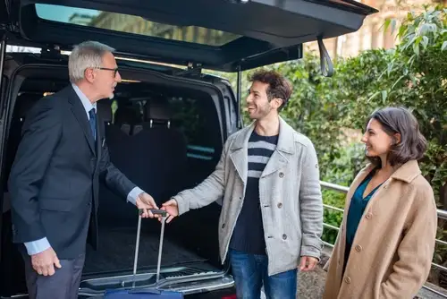 A man and woman entering a car with a suitcase. Enjoy the convenience of Private Chauffeur Services.