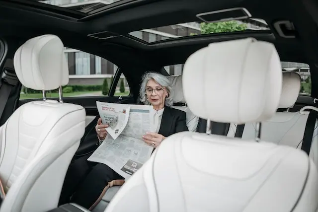 A Businesswoman Reading a Newspaper enjoying her comfortable transportation with corporate transportation services