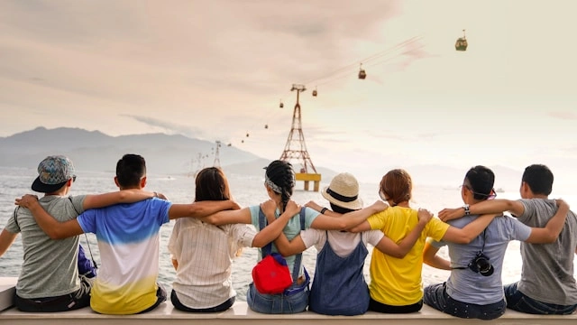 A group of people sitting by the sea represents group travel.
