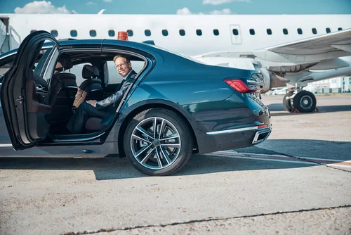 A businessman arrives at the private airport runway in a black luxury sedan, preparing to disembark as part of Lavish Ride’s premium FBO car service in Houston.