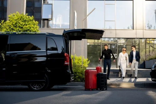 A professional chauffeur assists a group of passengers by transferring luggage from Houston Hobby Airport to a luxury van, representing Lavish Ride’s Houston Hobby Airport shuttle service.