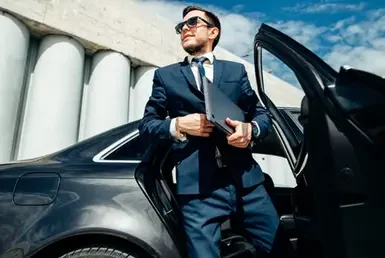 A fashionable businessman coming out of a Luxury black car service.
