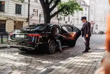 A girl arrives at her destination using a black car service, and the Chauffeur opens the car door for her after finishing her chauffeured black car ride.