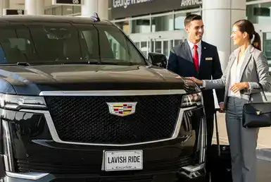 A professional chauffeur in uniform warmly welcomes a client at the airport beside a Cadillac Escalade ESV SUV bearing a "Lavish Ride" license plate, symbolizing luxury town car services.
