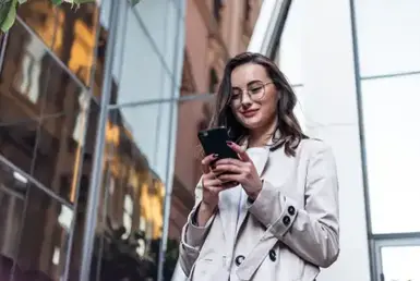 A young woman holds her smartphone to book a long-distance ride with private chauffeur services, highlighting seamless luxury transportation reservations.