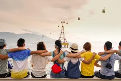 A group of people sitting by the sea represents group travel.