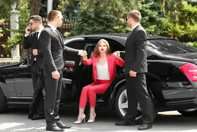 A young businesswoman exited a black executive car with a chauffeur and roadshow coordinators for the following road show location.