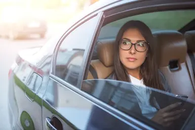 An elegant lady sits in the back seat of a limousine while enjoying a private limousine service for a private city tour.