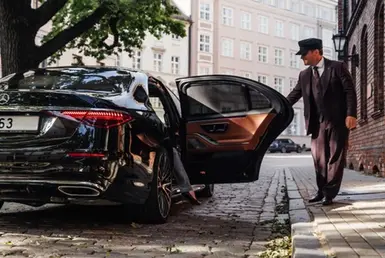 Limousine transfer chauffeur with chauffeur hat, stands by luxury car and open door for client. Mercedes Benz S500 S class w223 brand new model