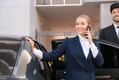 A young businesswoman is exiting a luxury car, utilizing a Houston real estate black car service.