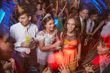 A group of teenagers in formal prom attire are enjoying the celebration inside a decorated hall, symbolizing Lavish Ride’s prom limo service in Houston.