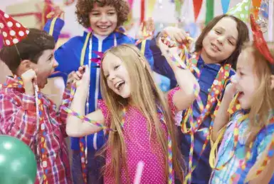 A joyful group of children dances and celebrates a girl’s birthday party, surrounded by balloons and decorations. They arrived in style using Elite Car Rental’s birthday party service in Houston.