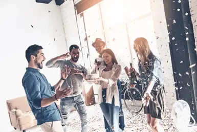A young man joyfully celebrates his birthday as confetti falls around him, surrounded by smiling friends. They created unforgettable memories using a premium Houston black car service.