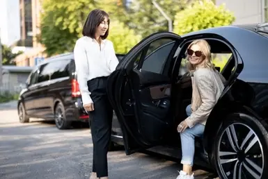 Limousine transfer chauffeur, opens a black luxury car door for client, symbolizing Insurance Company Executives car service in Houston