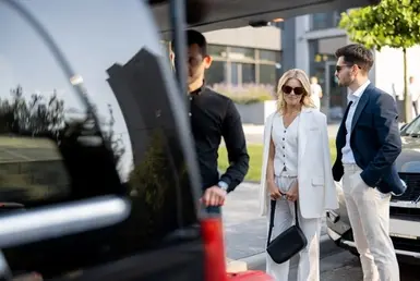A chauffeur helping an elegant man and woman loading there luggage in a black car, representing premium San Jose airport transfer and chauffeur services.