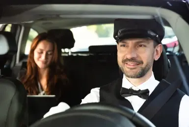 Chauffeur drives black luxury car as passenger works on iPad, symbolizing Las Vegas black car chauffeur services.