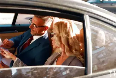 A couple reviewing paperwork in a car, possibly discussing chauffeur service options.