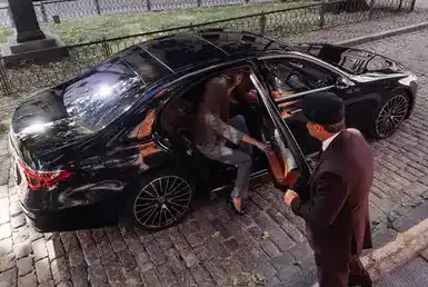 A distinguished woman gracefully enters a sleek black car, embodying the epitome of luxury and sophistication. Experience the finest Chauffeur Services.
