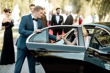 A young lady gets out of a black car with the help of her husband, apparently attending a social event, showing a luxury event transportation in Austin.