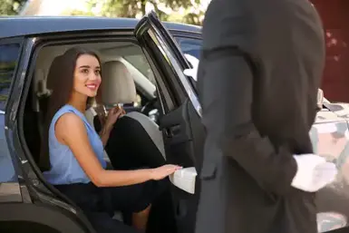 Driver opening car door for young businesswoman. Chauffeur service