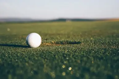 A golf ball near a golf hole on a grassy course, symbolizing recreational options in Houston, Texas.