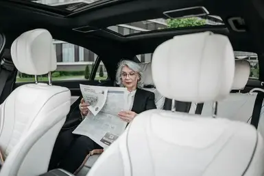 A Businesswoman Reading a Newspaper enjoying her comfortable transportation with corporate long distance transportation services. Symbolizing Vancouver Long Distance Transportation.