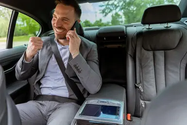 A satisfied CEO travelling using Houston executive-Car-Service, using his smartphone while travelling