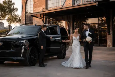 Bride and groom arriving at Station 3 Houston in a black Cadillac Escalade with Houston wedding professional chauffeur service