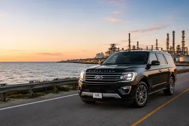 Executive and energy transportation service with a luxury SUV driving along the Gulf Coast at sunset.