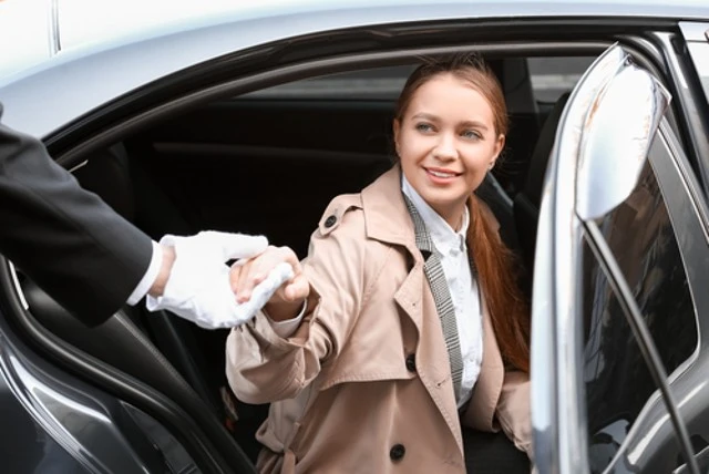 A woman out of a car and the chauffeur helps her. Perfect for Limo Services.