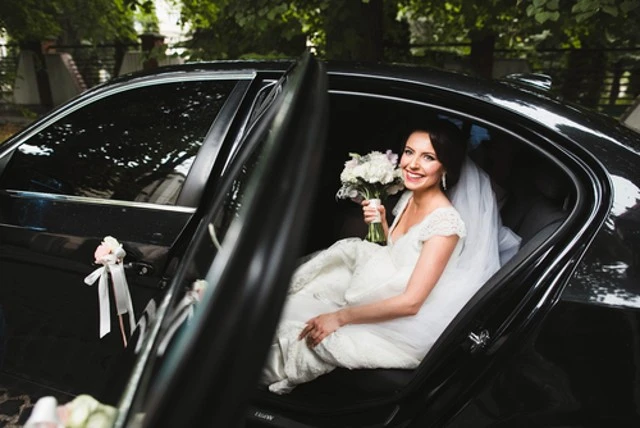 bride sitting in a stylish black car service.