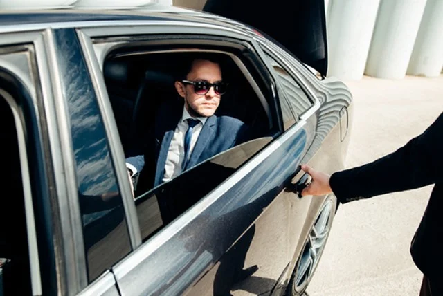 A businessman steps out of his private chauffeur service car in style.