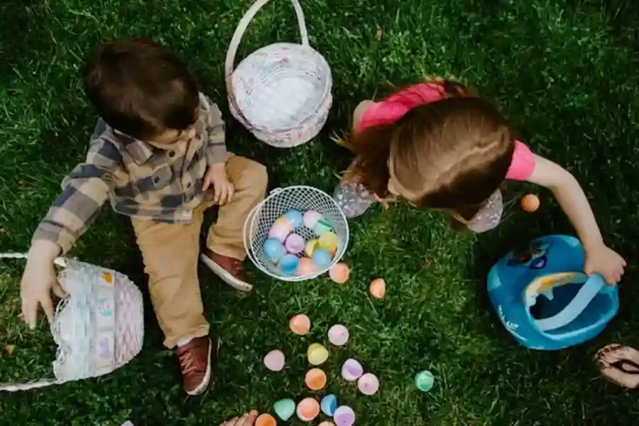 girl in green jacket playing with white and pink plastic balls on green grass field during in (Easter) American Holidays 